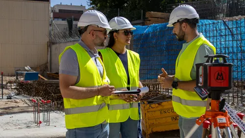 Equipo de Alza con casco y chaleco reflectante revisando trabajos en obra